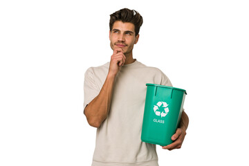 Young caucasian man holding a glass trash isolated looking sideways with doubtful and skeptical...