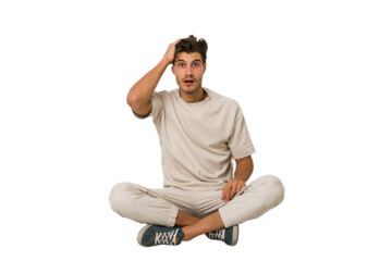 Young caucasian man sitting on the floor isolated on white background being shocked, she has remembered important meeting.