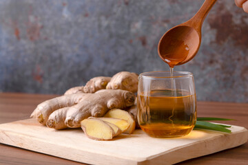 Cup of tea with ginger root on a wooden table, Ginger tea with and honey on a gray background.