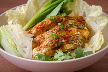  The fish is infused with a flavorful blend of chili and garlic, making it irresistibly appetizing. It's served with a variety of fresh vegetables.