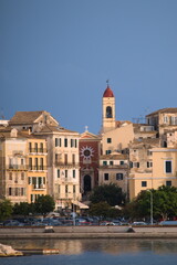Fototapeta premium Kerkyra (Corfu) boasts pastel-hued Venetian architecture, bustling Spianada Square, and the iconic Old Fortress against azure Ionian waters. 