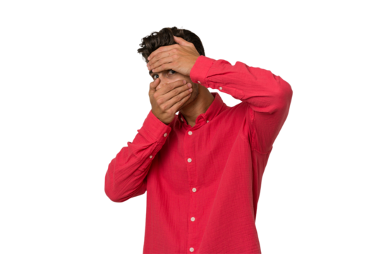 Young handsome caucasian man isolated on white background blink at the camera through fingers, embarrassed covering face.