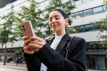 Confident woman scrolling through banking apps and map routes, blending finance and travel in a sleek street look