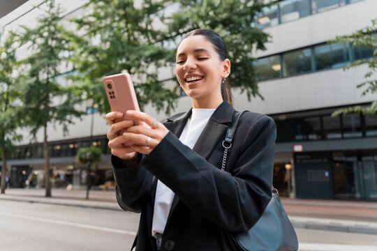 Urban professional smiling at phone, navigating city life with style while checking business updates and wellness tips on the go