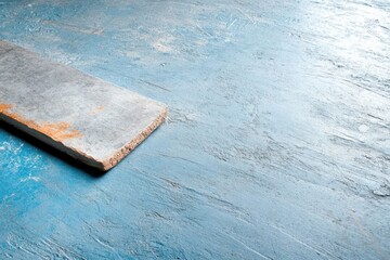 Concrete slab resting on textured blue surface showcasing wear and patina with light shadows