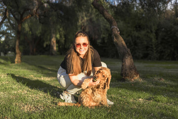 Woman shows affection to her cocker spaniel in a sunny park on a peaceful day
