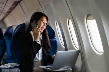 Business travel with a young woman smiling during a phone call on an airplane