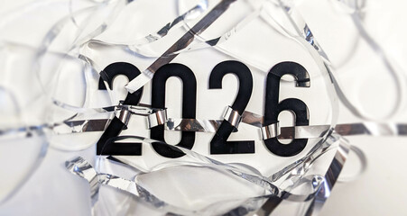New Year 2026 celebration with black numbers surrounded by ribbons scattered on a white background