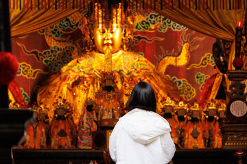 Asian Chinese people praying, Make a wish in front of Mazu or Matsu golden statue in Taiwan Temple