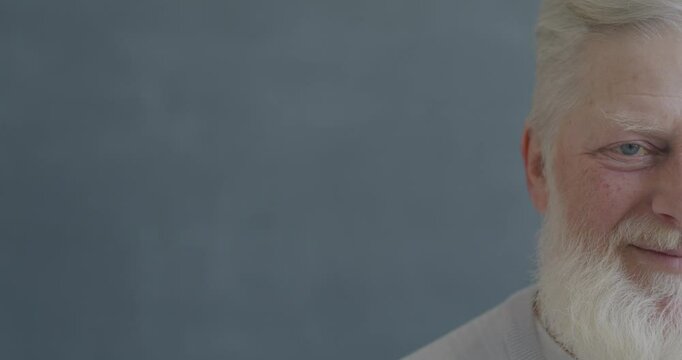 Close-up slow motion portrait of senior man half face smiling laughing looking at camera on black color background. People and good mood concept.