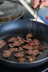 The chef fries veal in a frying pan. 