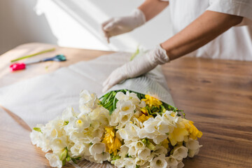 Flower arrangement process at a workshop with white and yellow blooms on a wooden table