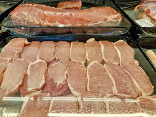 Fresh beef and pork displayed in a supermarket showcase, neatly wrapped in plastic for cleanliness and hygiene.