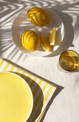 Plate with lemon fruits on the white plaster background with yellow striped pattern napkin with...