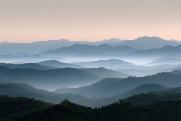 Obraz premium majestic mountain ridges at dawn enveloped in light fog with soft warm light illuminating peaks