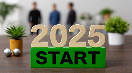 Wooden 2025 year letters sit atop a green block labeled start in front of three blurry people.