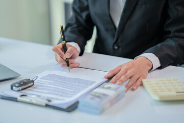 A man is offering a car quote to a customer with a calculator and money on the table.