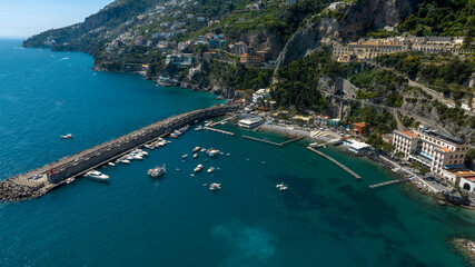 Naklejka premium Aerial view of the marina of Amalfi, located in the center of the town in the province of Salerno, in Campania, Italy. The sea is blue and crystal clear despite the presence of boats and ferries.