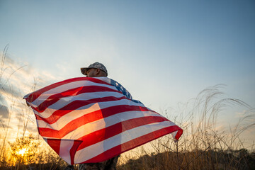 Hand Waving the Flag of the United States of America in memorial day . Us soldier holding American...