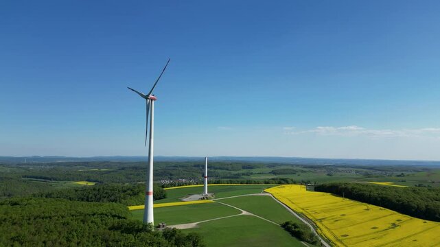 Panoramablick auf eine rotierende Windturbine f&uuml;r Stromerzeugung und einen unvollendeten Turm, Wind Energie und Technologie, Nachhaltige Energie Konzept, 4K, Aerial, Kamerafahrt