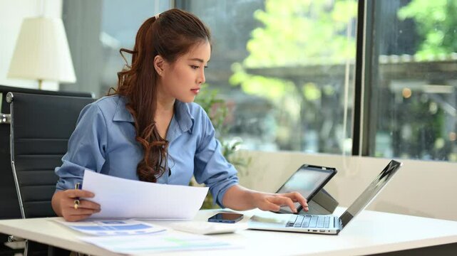 Business woman using tablet and laptop for doing math finance on an office desk, tax, report, accounting, statistics