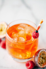 Fresh sparkling berry drink with passion fruits and raspberries in wine glass.