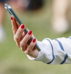 A woman is holding a cell phone with her right hand