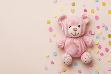 Obraz premium Pink crocheted teddy bear surrounded by colorful confetti on a pale pink background a cute baby shower image