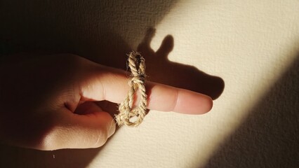 Obraz premium Child's finger with rope ring shadow on beige surface. Possible use educational material or child's play