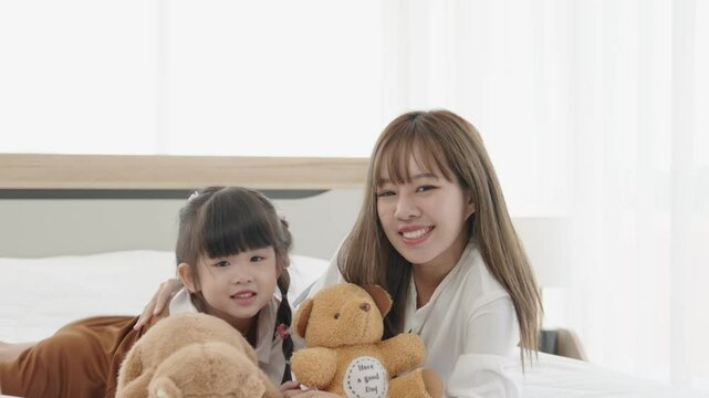 Happy mother and daughter share indoor happiness with teddy bears, creating joyful moments together.