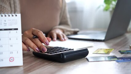 financial planning concept with woman hand calculating monthly costs, noting down debts, credit card payments, and upcoming due dates on a calendar