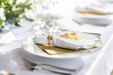 A wedding table covered with a white tablecloth, decorated with flowers, candles, glasses and cutlery