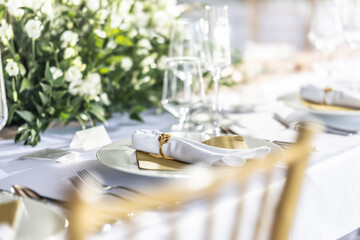 A wedding table covered with a white tablecloth, decorated with flowers, candles, glasses and cutlery
