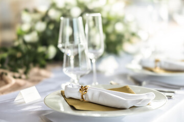 A wedding table covered with a white tablecloth, decorated with flowers, candles, glasses and cutlery