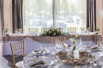 A wedding table covered with a white tablecloth, decorated with flowers, candles, glasses and cutlery