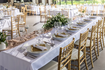 A wedding table covered with a white tablecloth, decorated with flowers, candles, glasses and cutlery