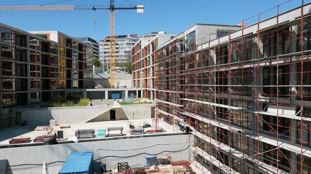 Modern residential buildings under construction with scaffolding and cranes, captured on a clear sunny day