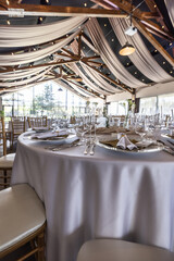 Wedding setting and decorated tables in a beautiful modern interior of a performance hall with a modern light ceiling of wooden construction