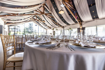 Wedding setting and decorated tables in a beautiful modern interior of a performance hall with a modern light ceiling of wooden construction
