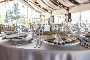 Wedding setting and decorated tables in a beautiful modern interior of a performance hall with a modern light ceiling of wooden construction