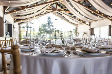 Wedding setting and decorated tables in a beautiful modern interior of a performance hall with a modern light ceiling of wooden construction