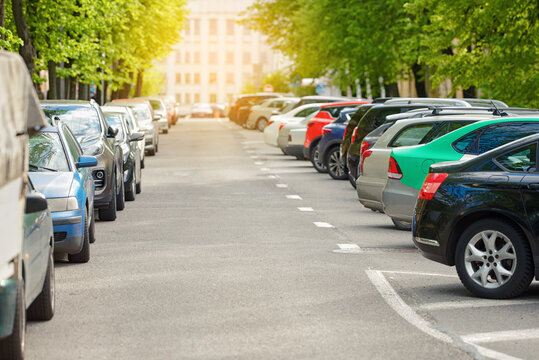Urban street with cars parked tightly on both sides, diagonal parking on one side and angled parking on the other, illustrating city congestion, limited space. Vehicles occupying both sides of road