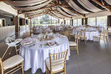 Wedding setting and decorated tables in a beautiful modern interior of a performance hall with a modern light ceiling of wooden construction