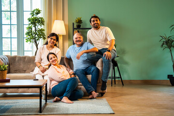 Obraz premium Laughing together while sitting indoors, cheerful Indian family enjoying quality time on sofa