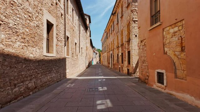 Narrow cobblestone alley lined with pastel shuttered buildings and boutique entrances in the heart of Brescia Old Town, Lombardy, Italy