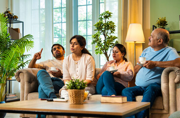 Discussing topic over tea, Indian family sitting together on couch having an important talk