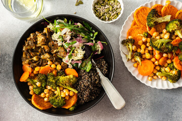 A nutritious breakfast bowl with black quinoa, avocado, roasted chicken, sweet potatoes, zucchini, and broccoli, paired with a fresh salad of cabbage, radish, chia, and sesame seeds
