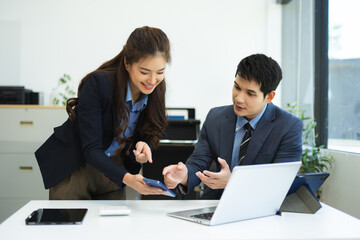 Asian businessman and woman workers talking on the smartphone and using laptop Professionals in Teamwork Finance, Marketing, and Success