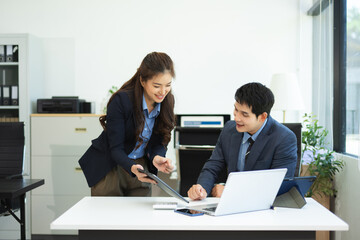 Asian businessman and woman workers talking on the smartphone and using laptop Professionals in Teamwork Finance, Marketing, and Success