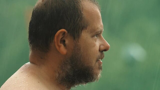 A man lifts his face to the sky during a storm, eyes closed, as if letting go of thought and merging with the raw force of nature.
